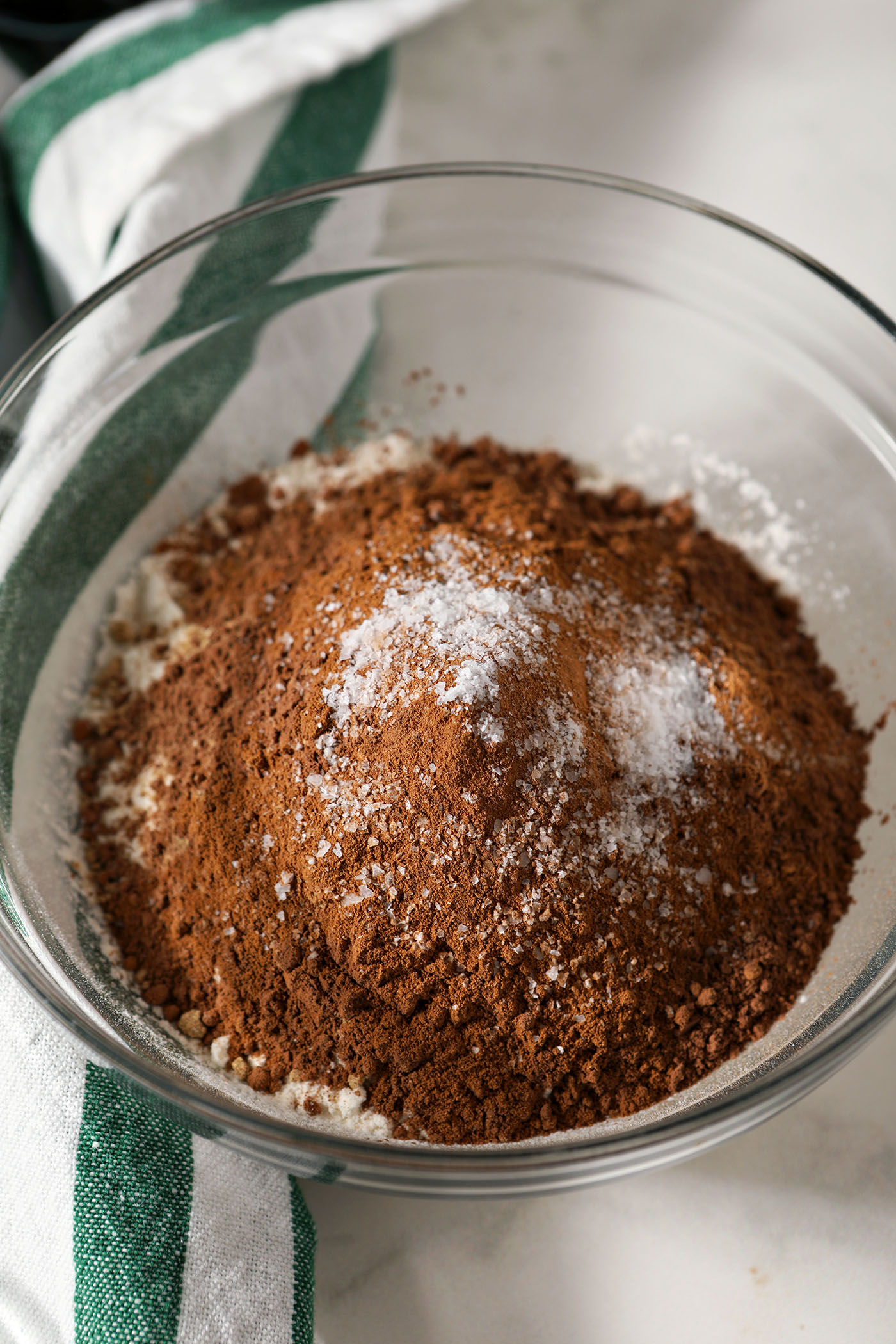 Dry ingredients in a bowl next to a green and white striped linen