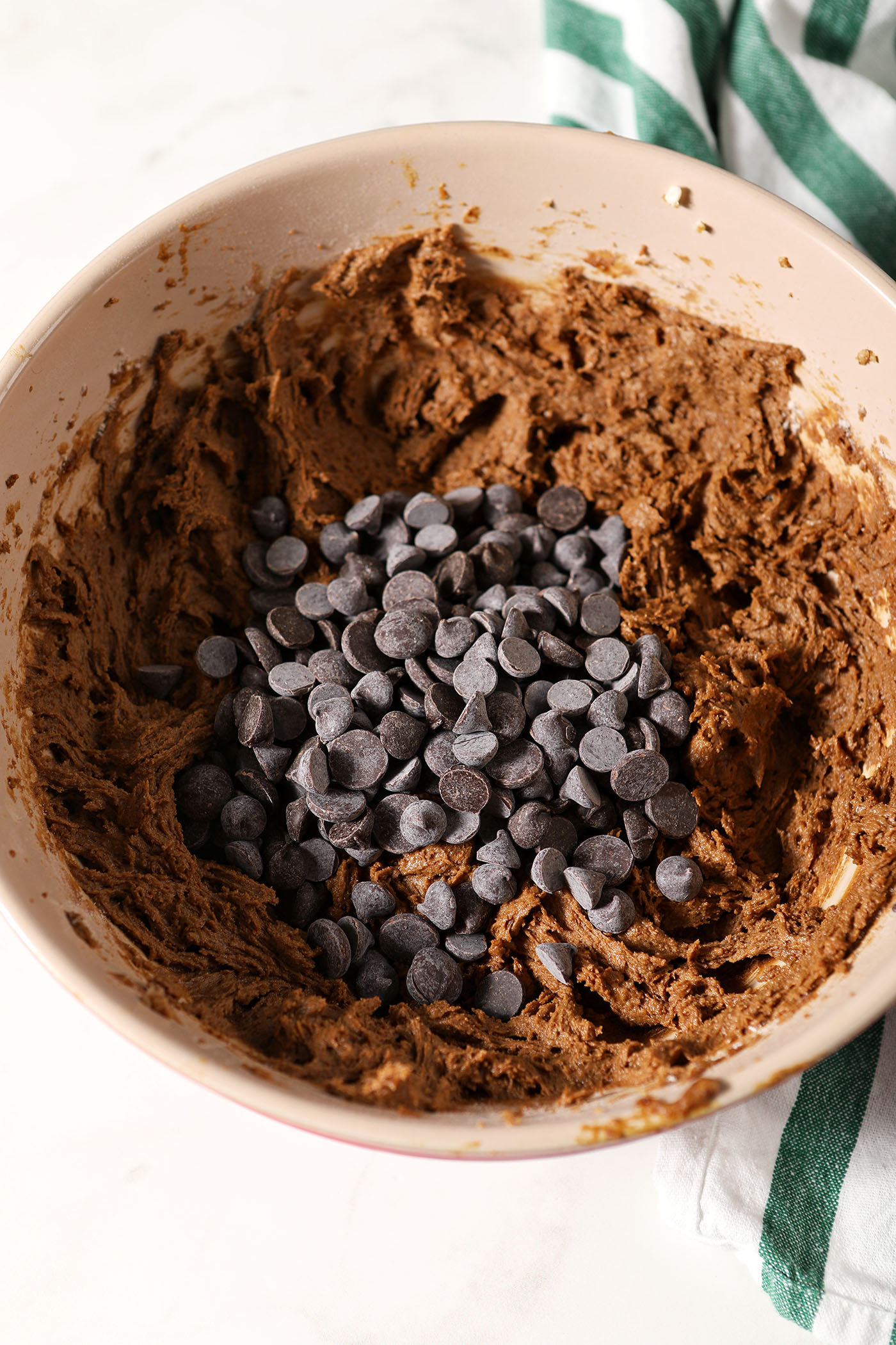 Chocolate chips sit on top of cookie dough, before mixing in