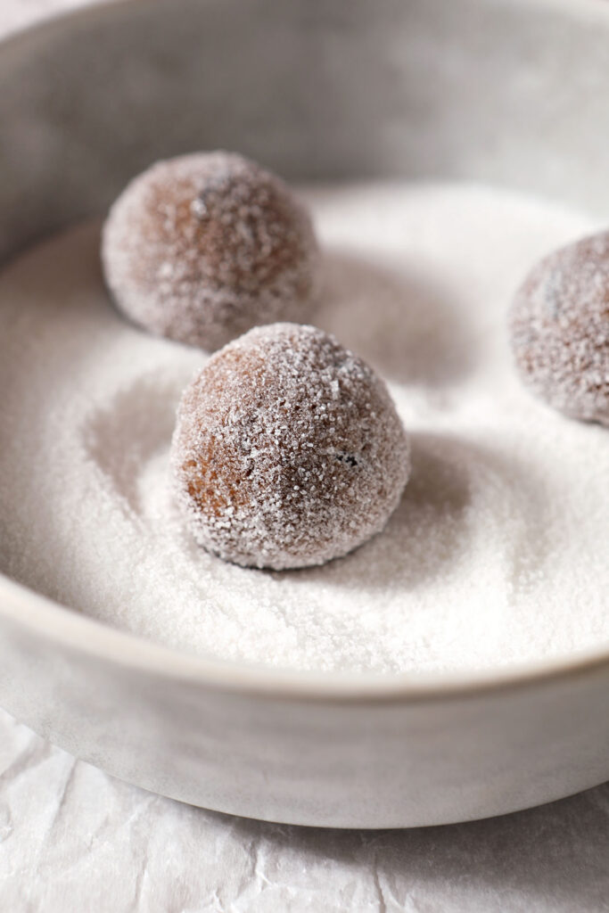 Three cookie dough balls rolled in sugar in a bowl