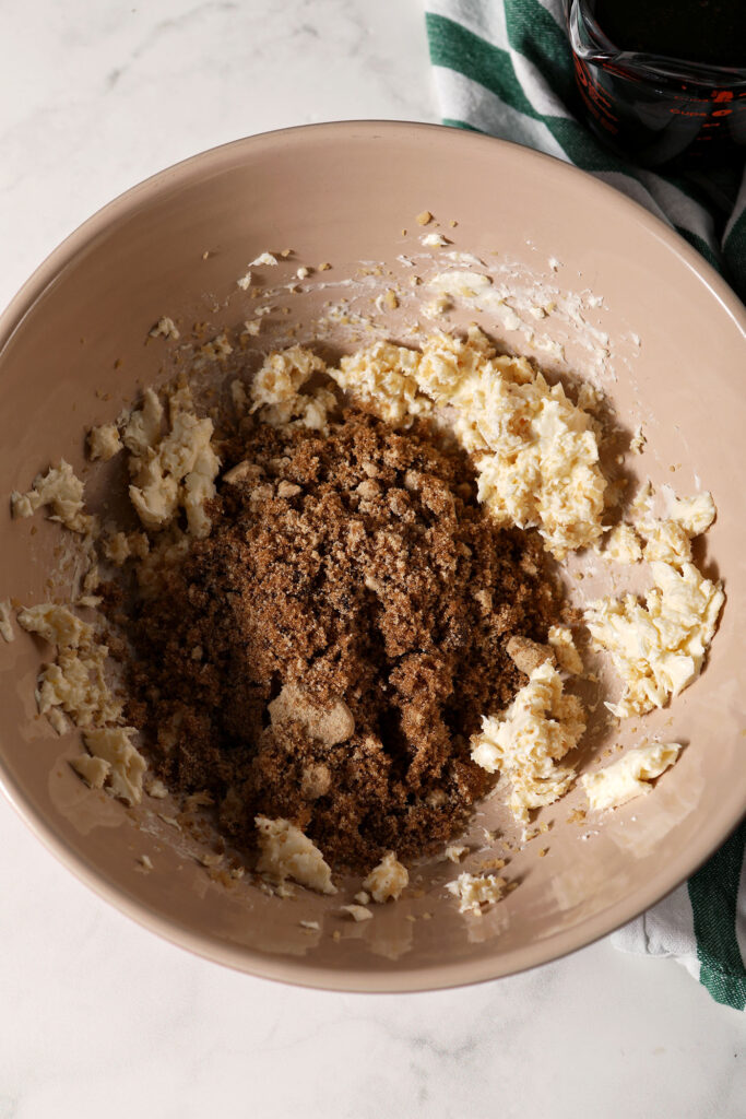 Dark brown sugar on top of butter and ginger in a bowl