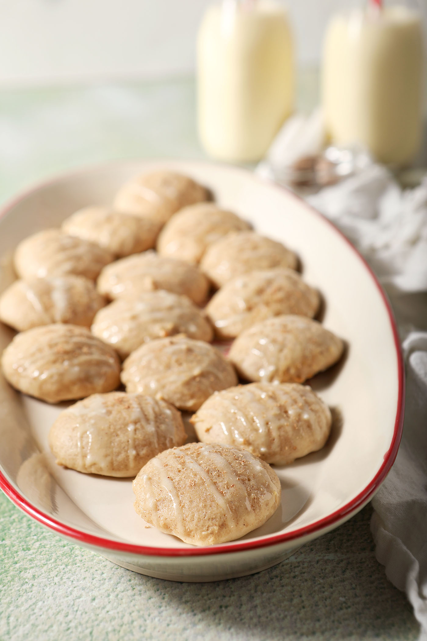 A plate of eggnog cookies in front of two bottles of eggnog