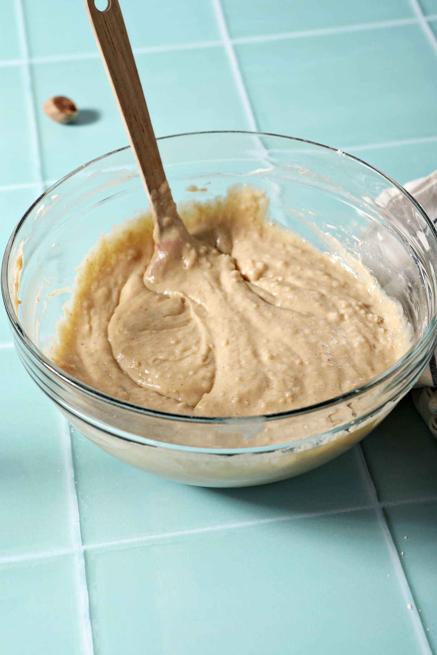 Eggnog muffin batter in a bowl on a green tiled surface