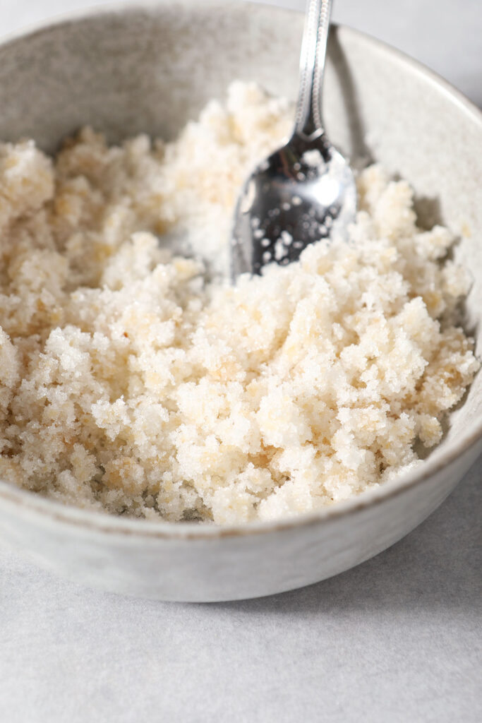 A ginger sugar mixture in a grey bowl with a spoon