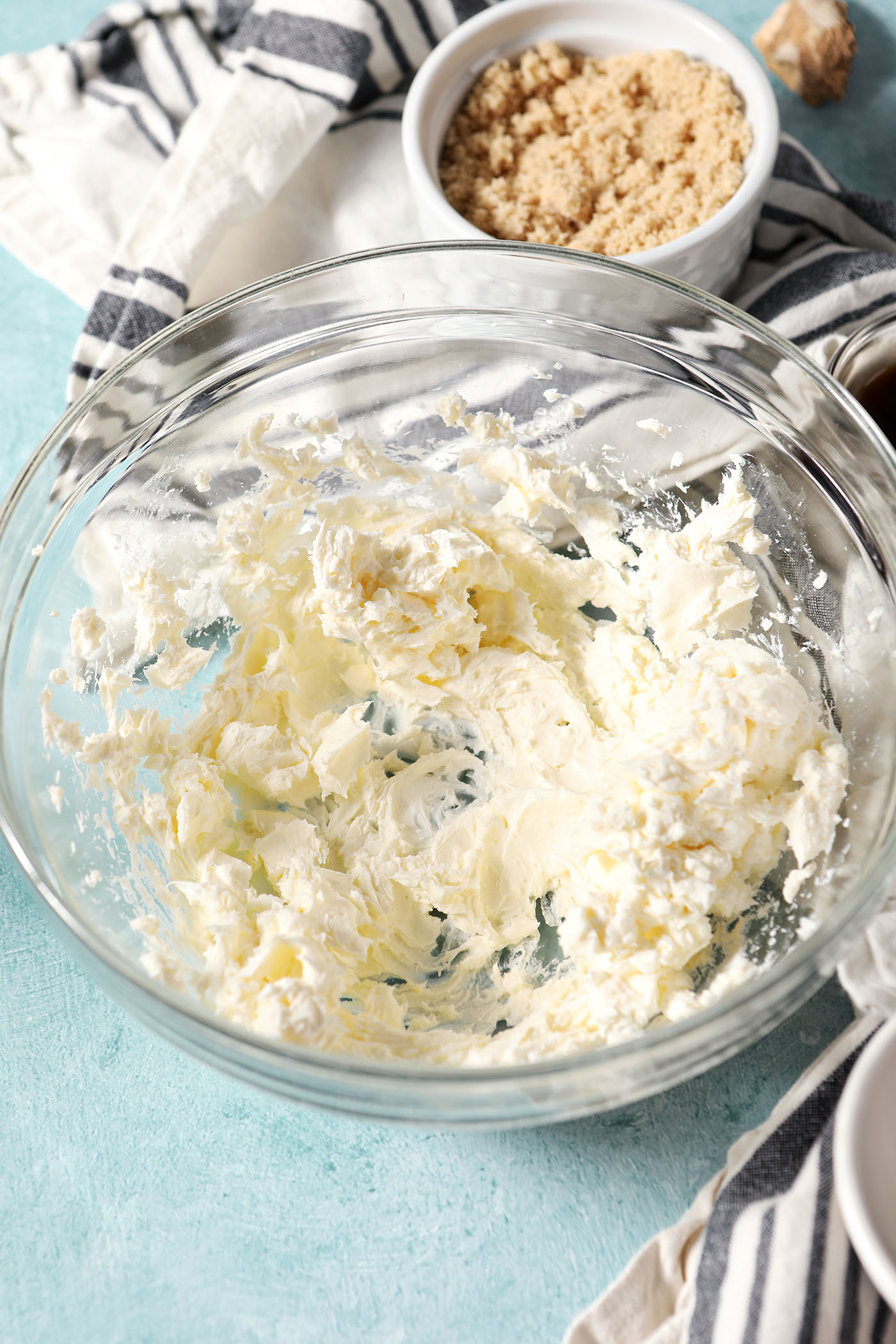 Whipped cream cheese in a glass bowl on a teal surface