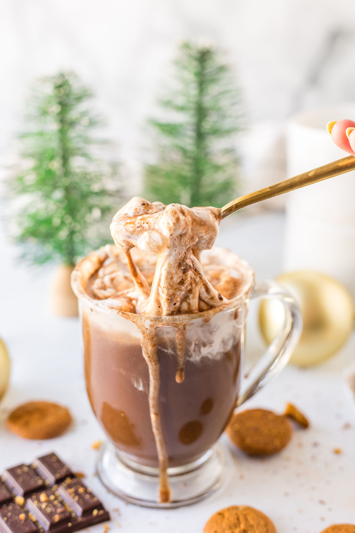 A spoon stirs marshmallow fluff into a mug of hot cocoa