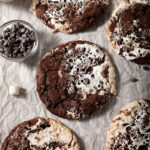 A sheet pan of baked hot cocoa cookies, surrounded by marshmallows and chocolate chips