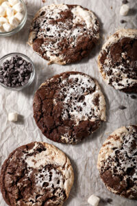 A sheet pan of baked hot cocoa cookies, surrounded by marshmallows and chocolate chips
