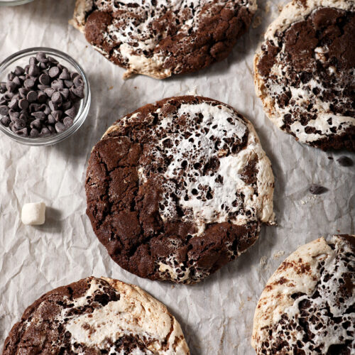 A sheet pan of baked hot cocoa cookies, surrounded by marshmallows and chocolate chips