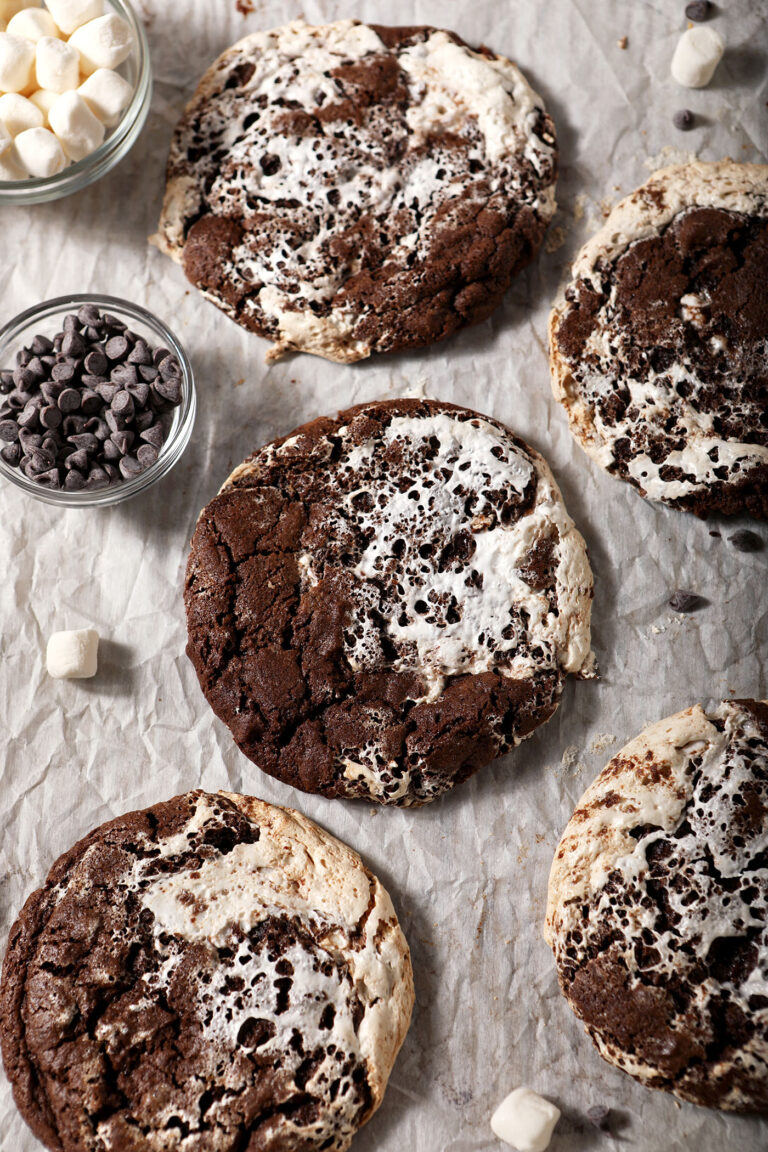 A sheet pan of baked hot cocoa cookies, surrounded by marshmallows and chocolate chips