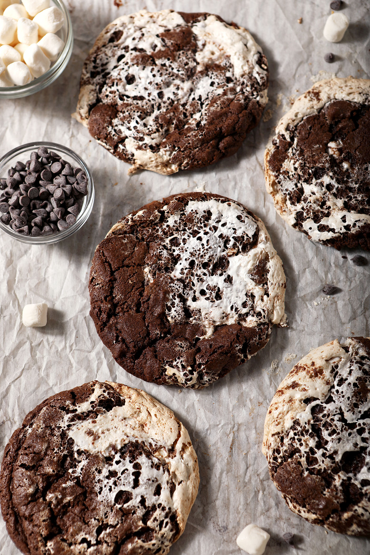 A sheet pan of baked hot cocoa cookies, surrounded by marshmallows and chocolate chips