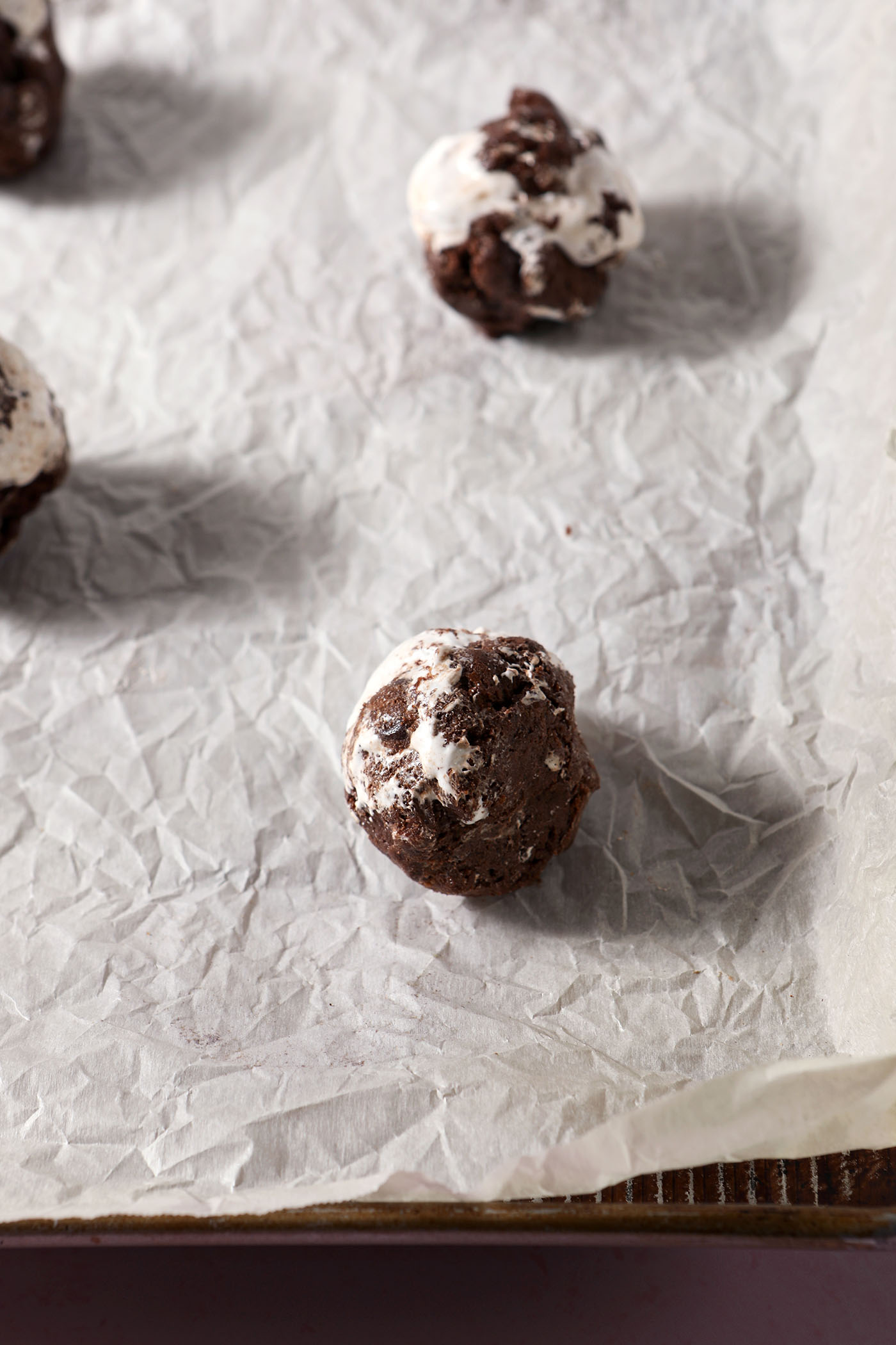 Rolled hot chocolate cookie dough balls on a parchment-lined sheet pan before baking