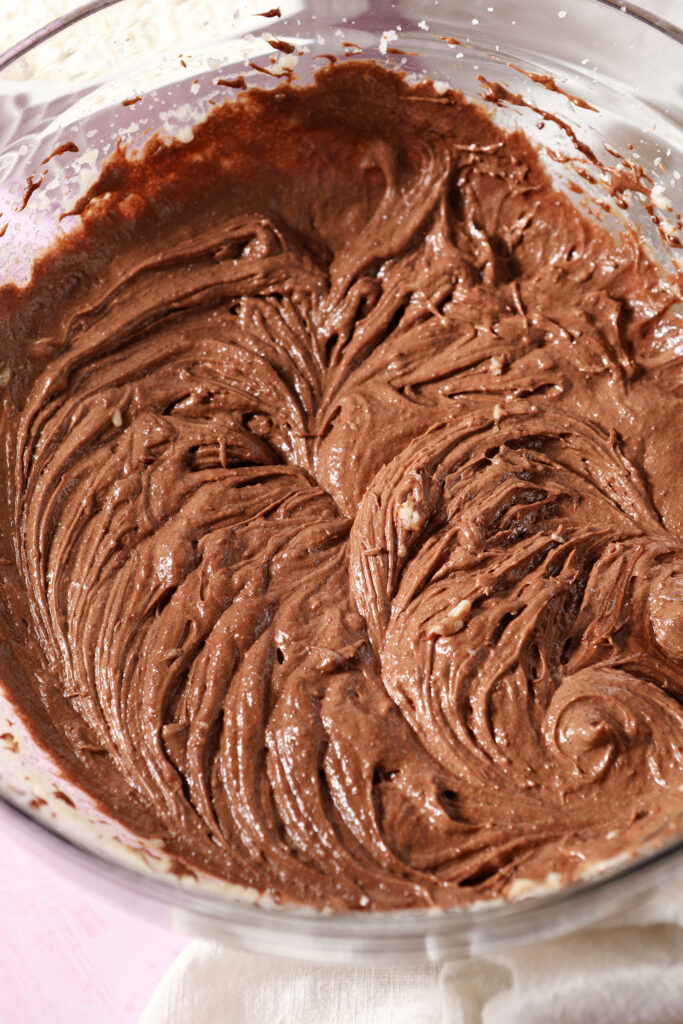 Whipped wet cookie ingredients in a bowl on a pink surface
