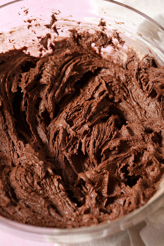 Chocolate cookie dough in a bowl on a pink surface
