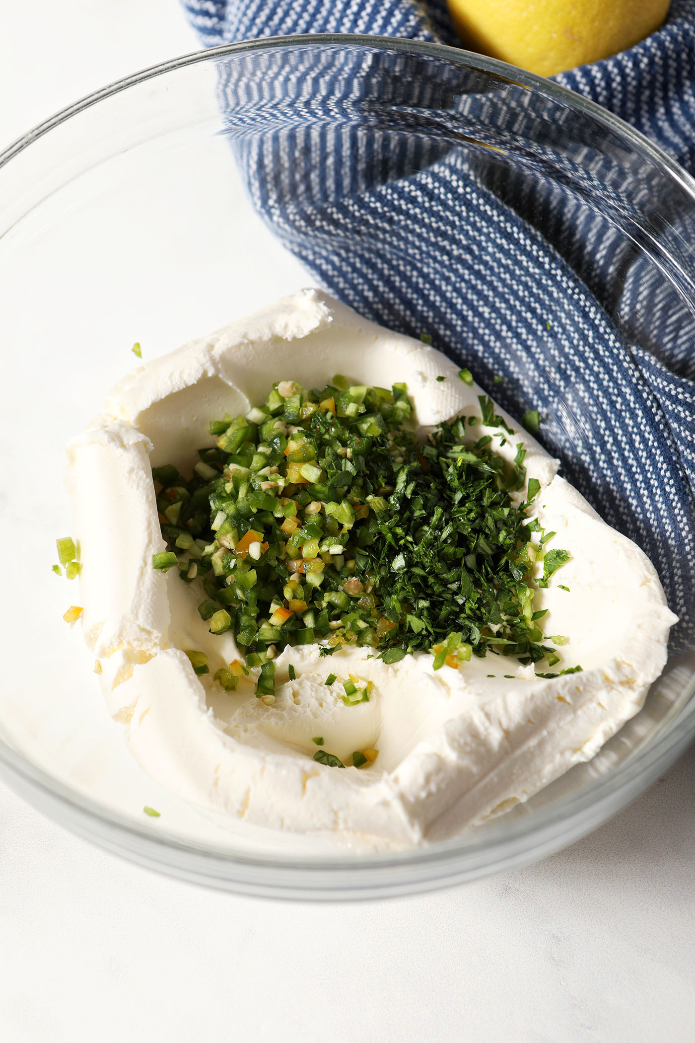 Softened cream cheese with chopped jalapeños and spices on top of it, before mixing