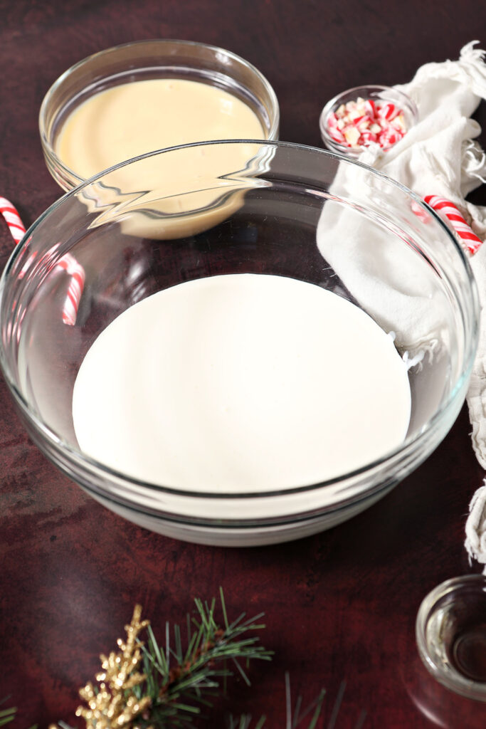 Heavy cream in a bowl on a dark red surface next to a light linen