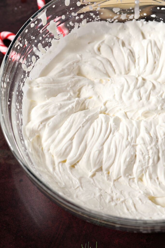 Whipped cream in a bowl on a dark red surface