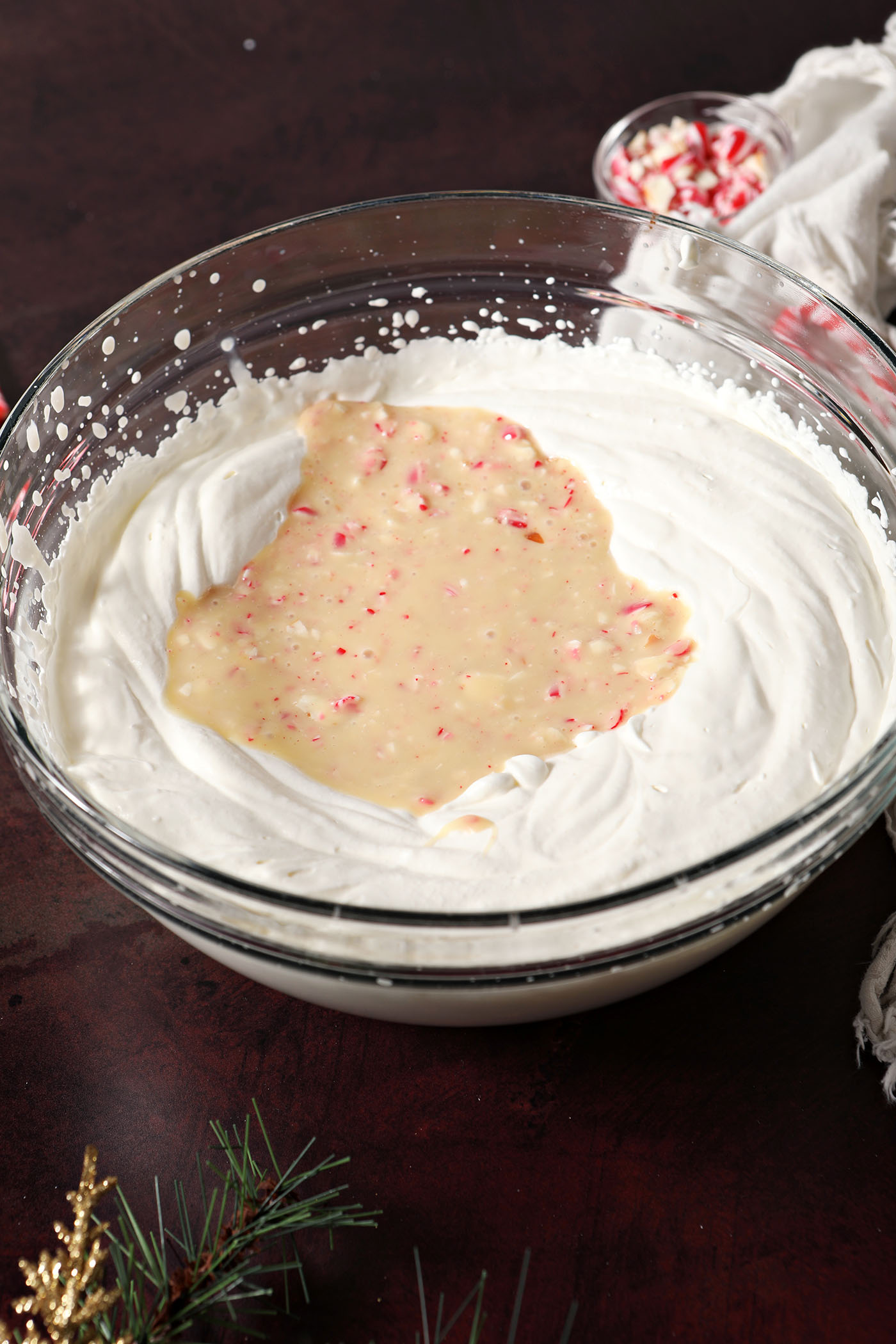 Ingredients in a bowl to make No Churn Peppermint Ice Cream, before mixing, on a dark red surface