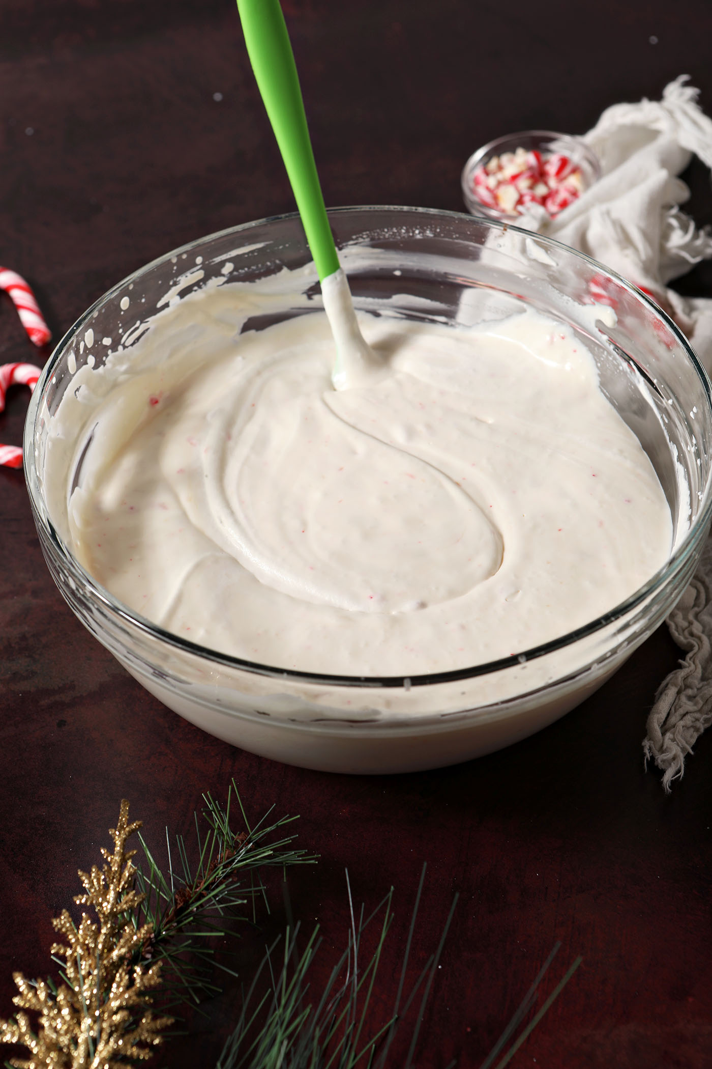 No Churn Peppermint Ice Cream after mixing in a bowl on a dark red surface
