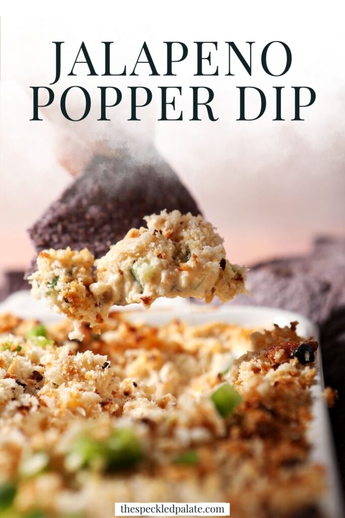 Close up of a hand dipping a blue corn tortilla chip into baked jalapeño popper dip with the text jalapeno popper dip