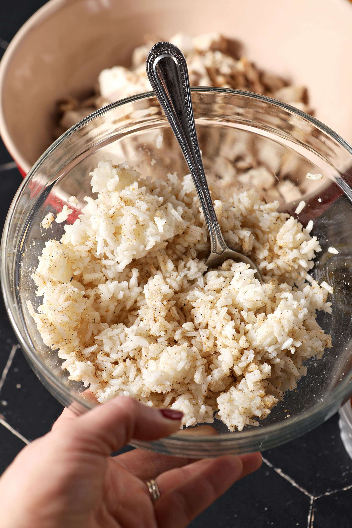 A hand holds a bowl of seasoned white rice