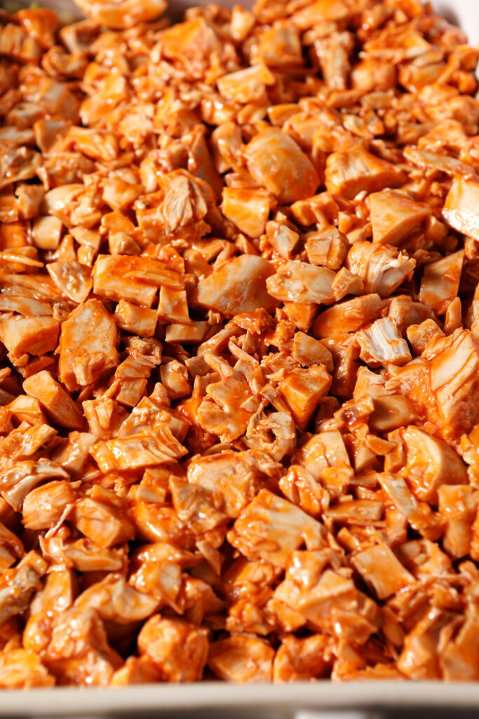 Close up of chopped buffalo chicken in a casserole dish