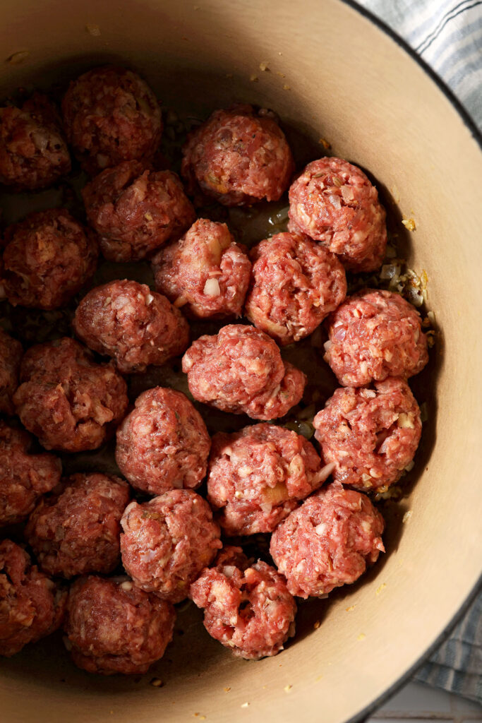 Raw meatballs in a large dutch oven before cooking