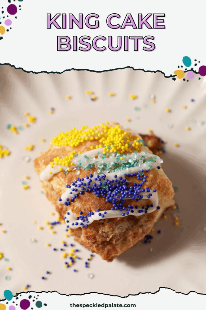 overhead of a biscuit drizzled with icing and sprinkled with gold, green and purple sprinkles on a plate with the text king cake biscuits