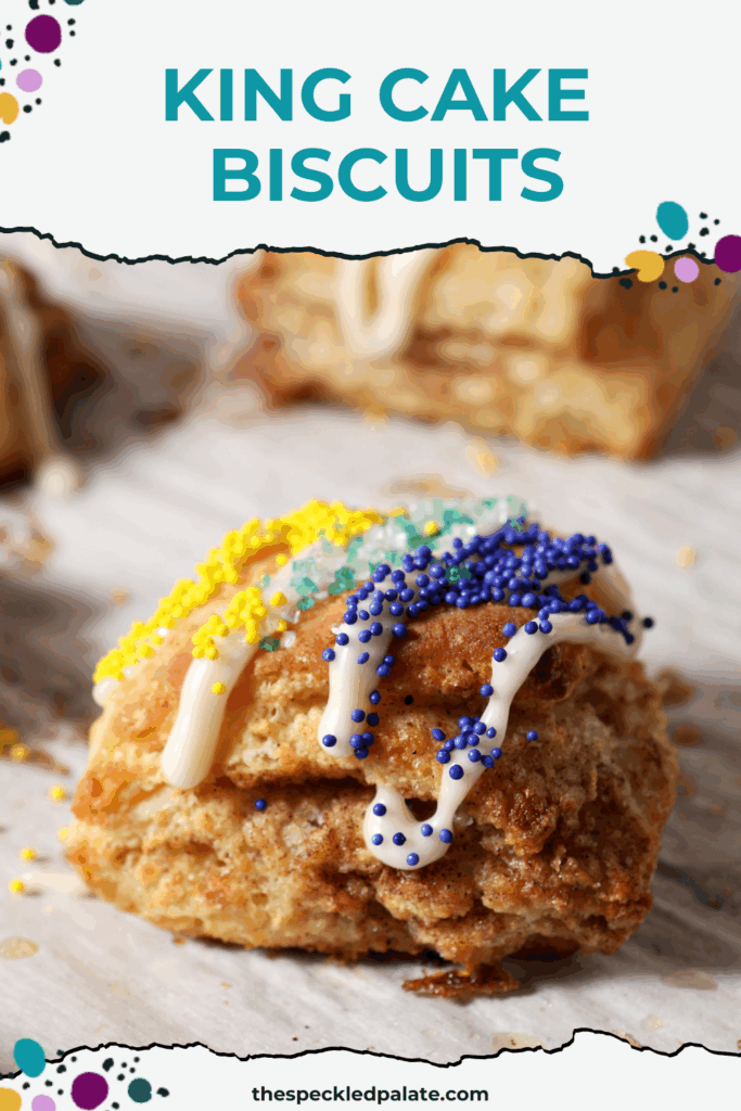 A cinnamon sugar biscuit decorated like a king cake for Mardi Gras sits on a sheet pan near other biscuits with the text king cake biscuits
