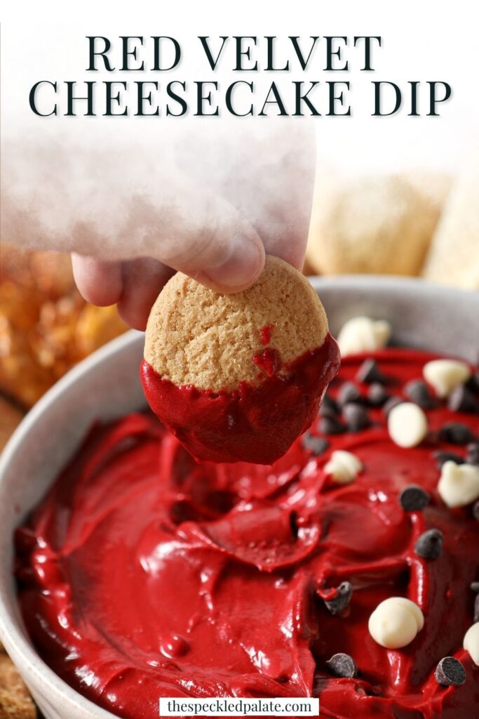 A hand dips a vanilla wafer cookie into red velvet dip with the text red velvet cheesecake dip