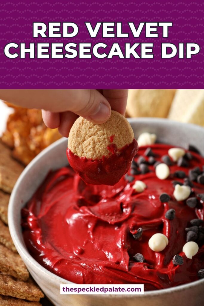 A hand dips a vanilla wafer cookie into red velvet dip with the text red velvet cheesecake dip