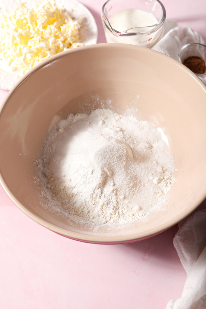 Dry ingredients in a large bowl before mixing for biscuits on a pink surface