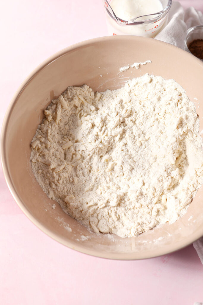 Flour and butter mixed in a large bowl on a pink surface