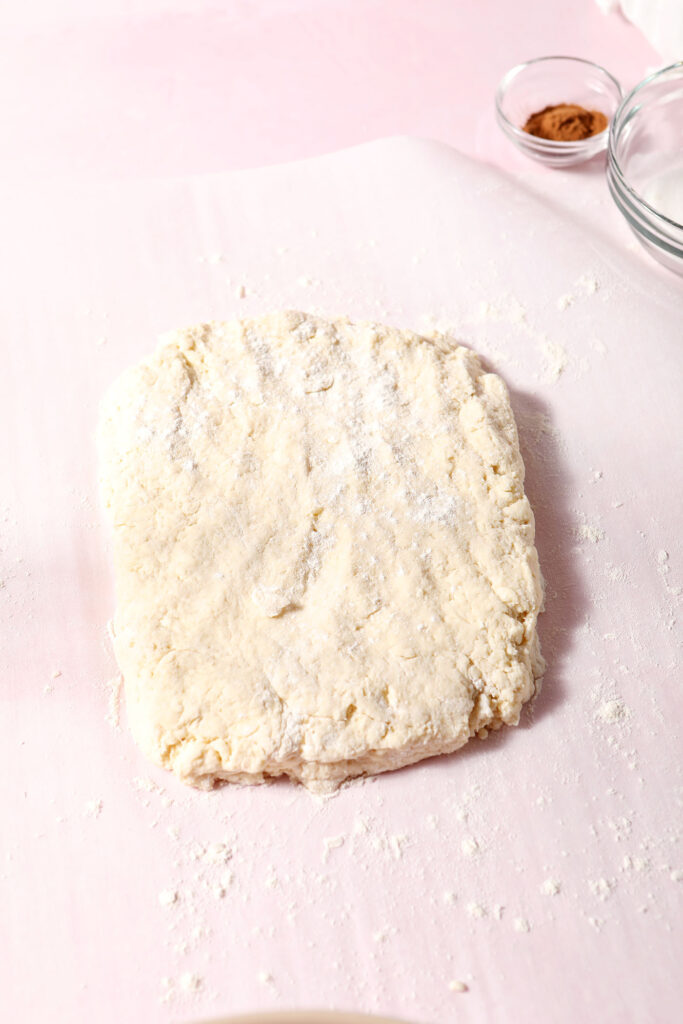 A square of biscuit dough on a floured surface