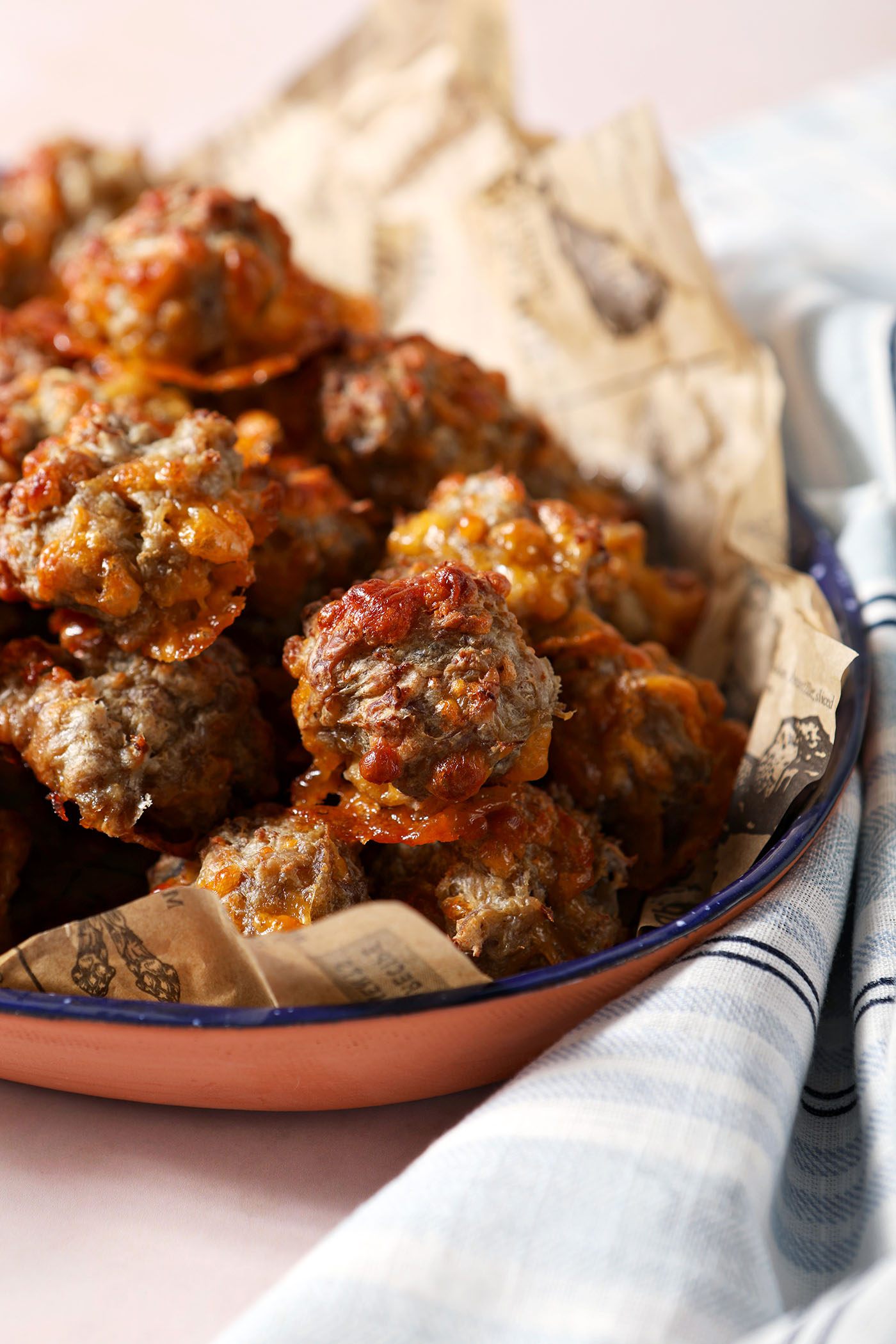 A platter of homemade sausage balls on a stone surface next to a blue and white striped linen
