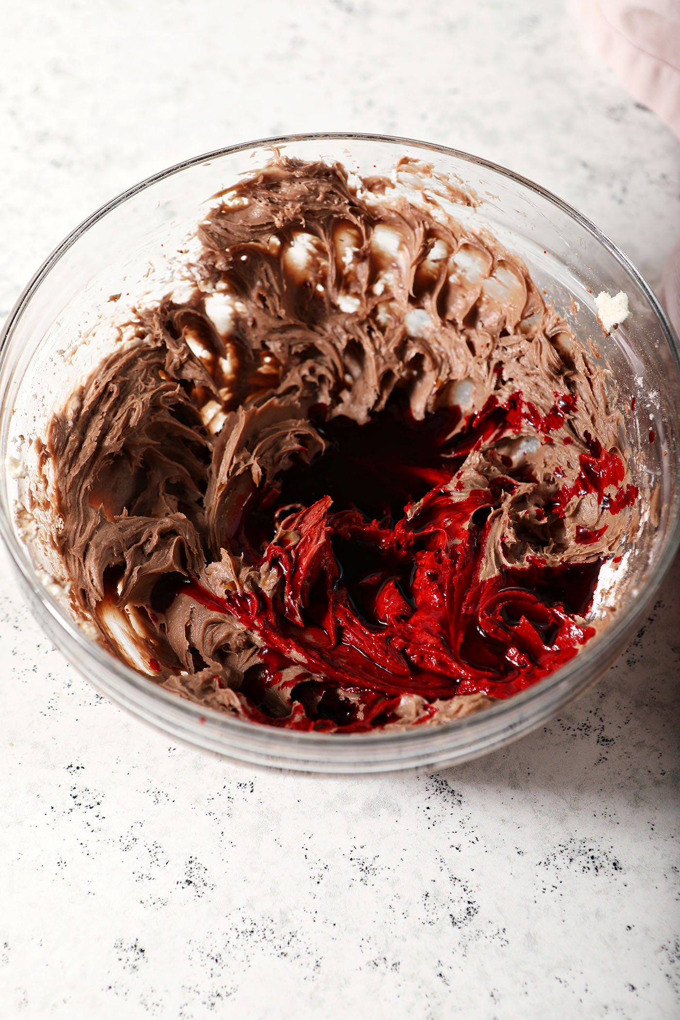 Food coloring and vanilla sit on top of other red velvet dip ingredients in a bowl before blending