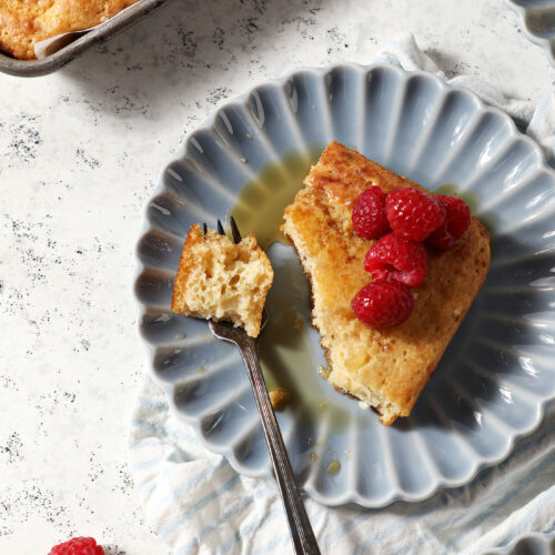 A fork holds a bite of a sheet pan pancake on a blue plate