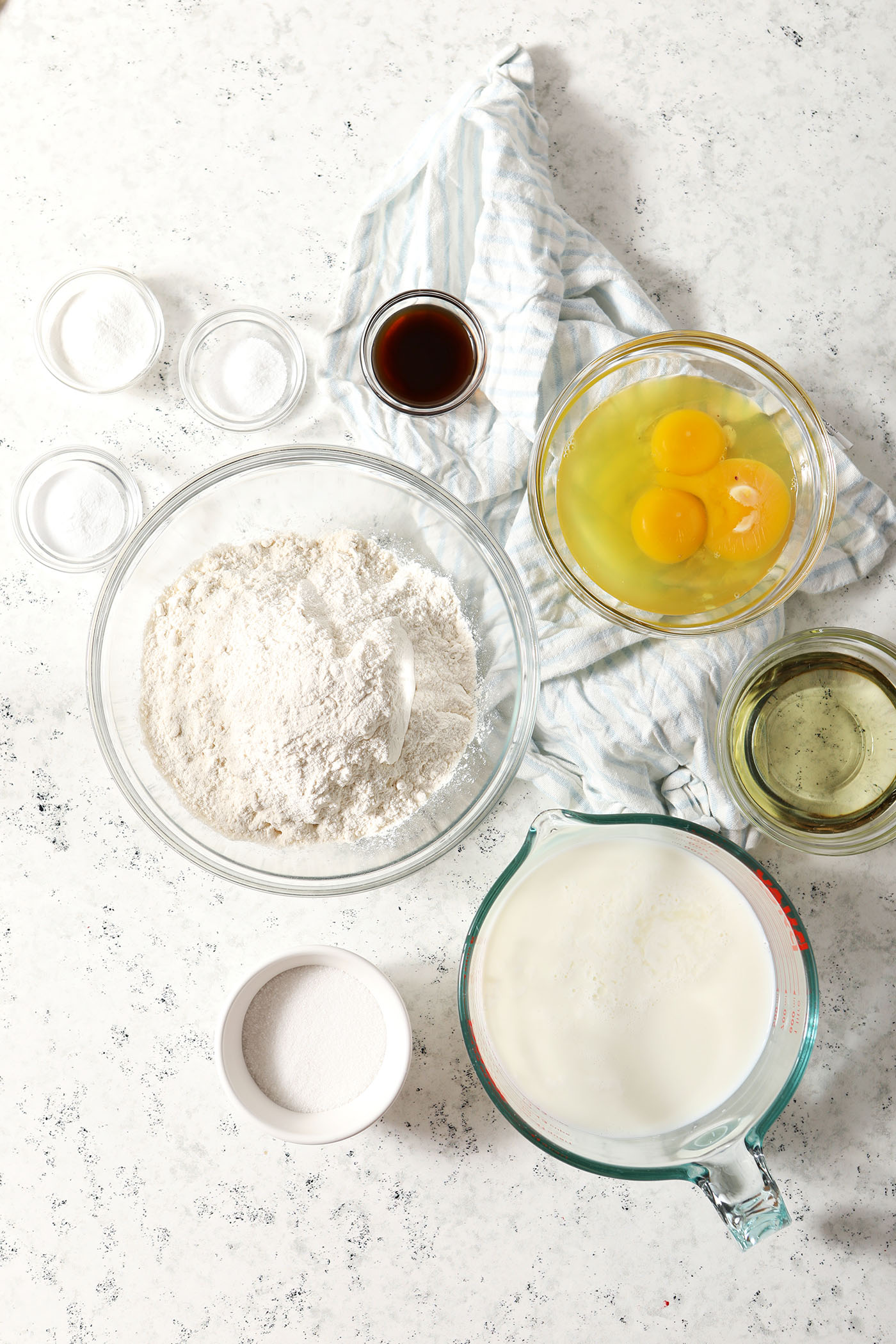 Bowls holding ingredients to make pancakes on a stone surface