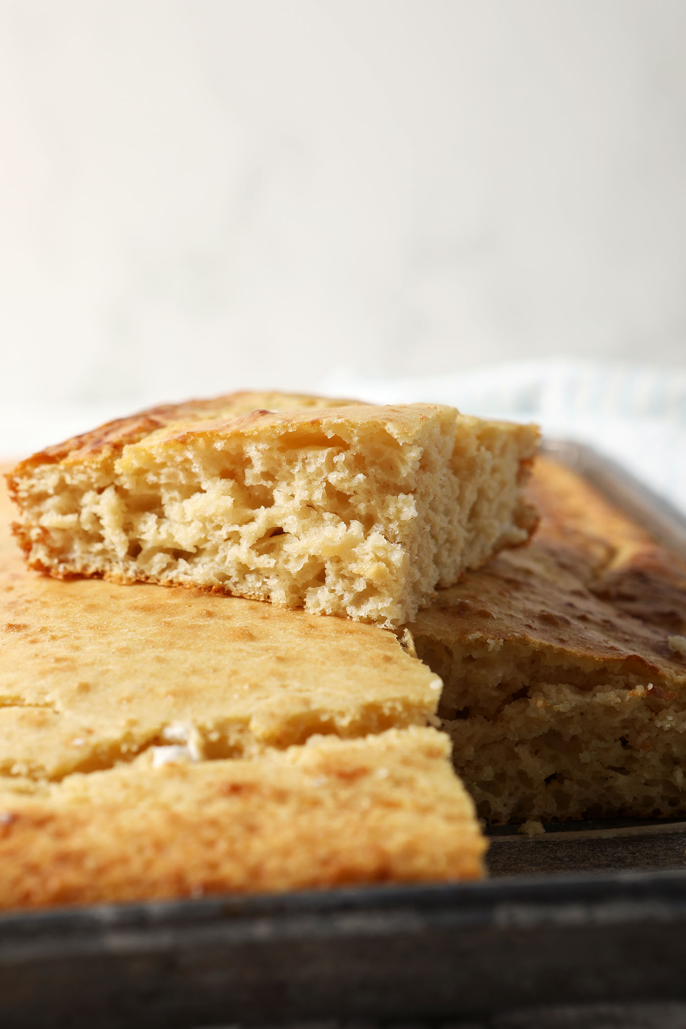 A square slice of sheet pan pancake on top of the rest of the pancakes on the sheet pan