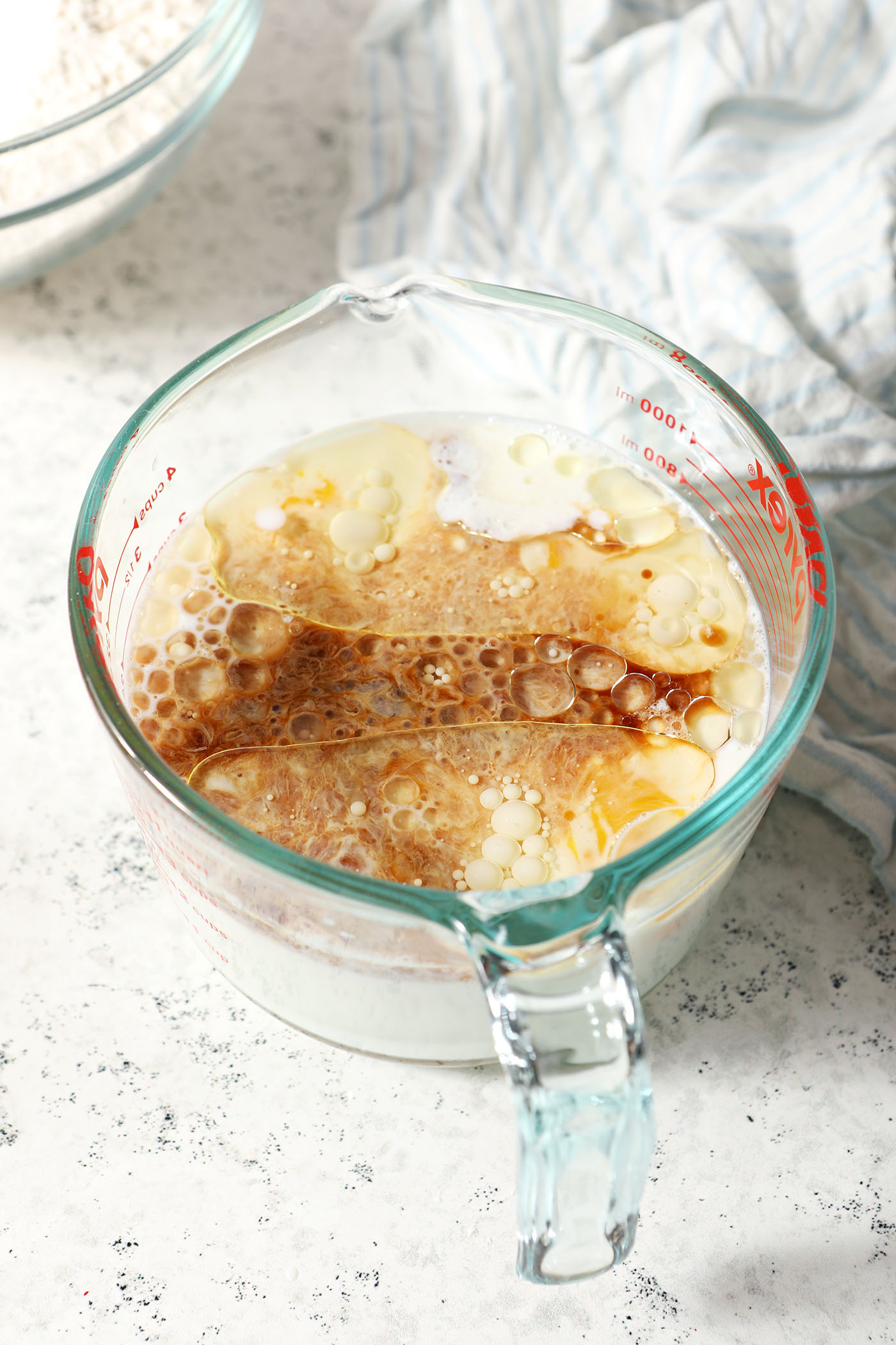 Wet ingredients in a liquid measuring cup before mixing on a stoneware surface
