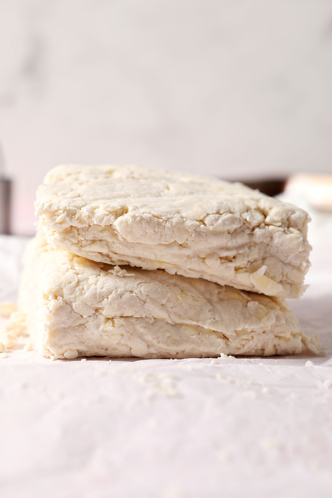 Halved biscuit dough sits on top of itself on a sheet of parchment paper