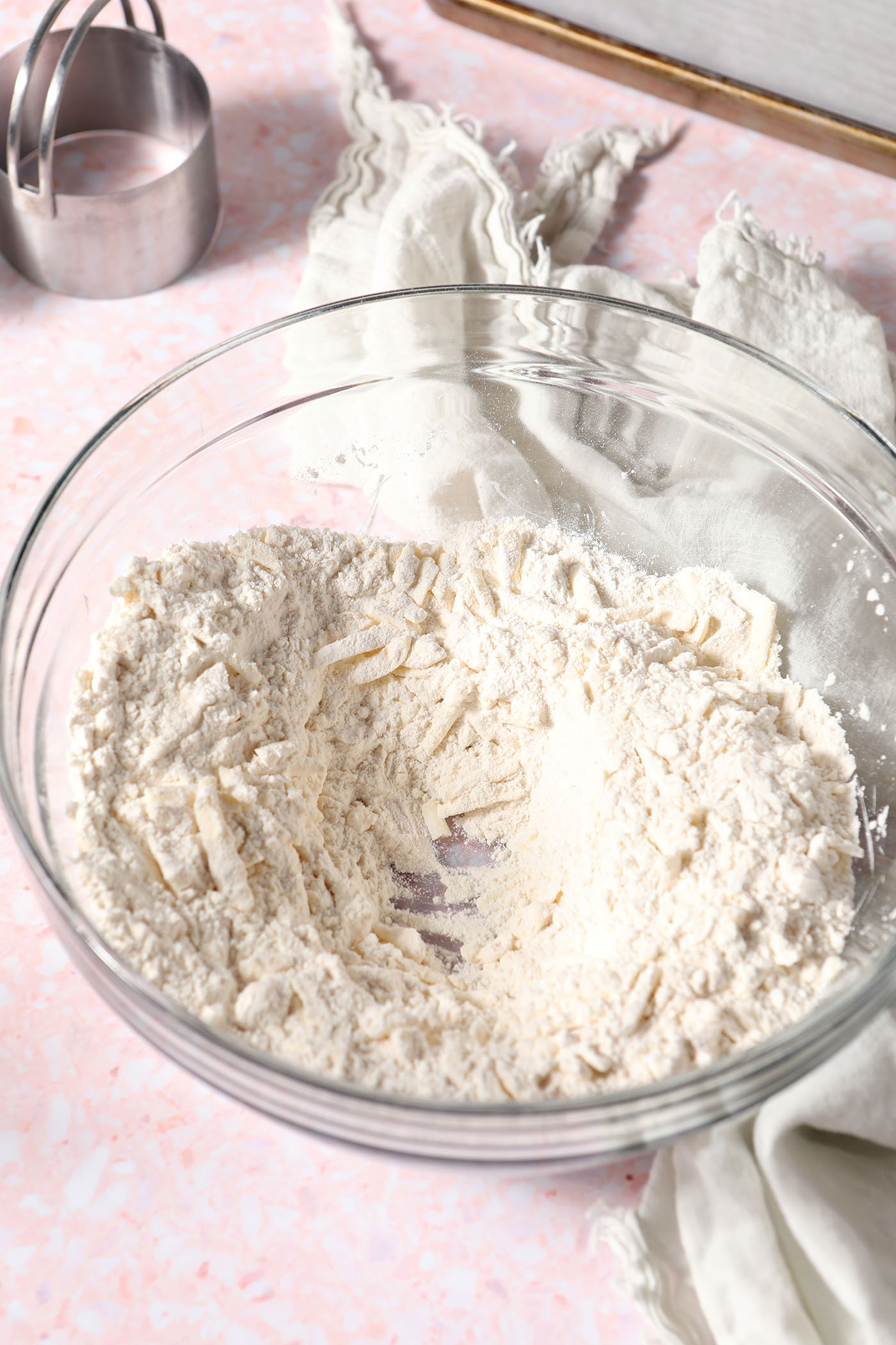 Mixed flour and shredded frozen butter in a bowl on a pink terrazzo surface