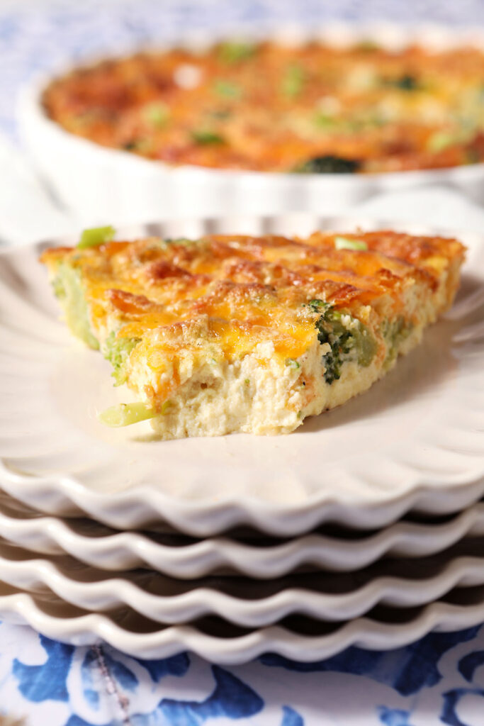 A slice of quiche on a stack of plates with a bite taken out of it