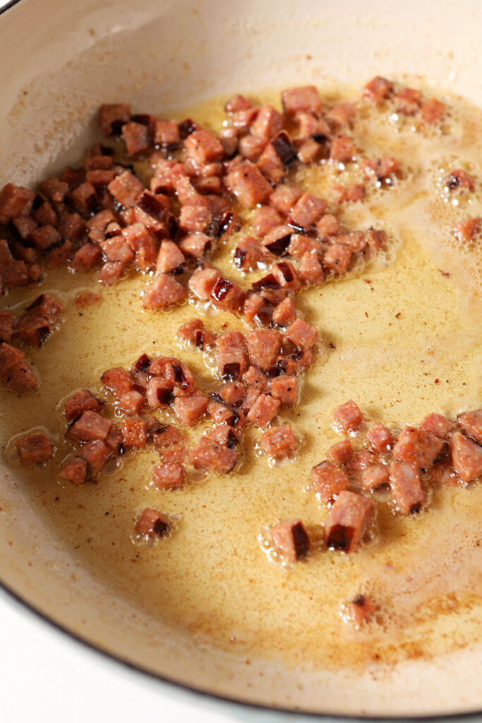 Diced andouille sausage sizzles in a pan