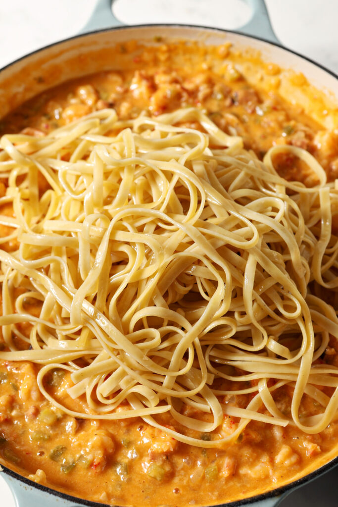 Noodles on top of a crawfish sauce in a pan before mixing