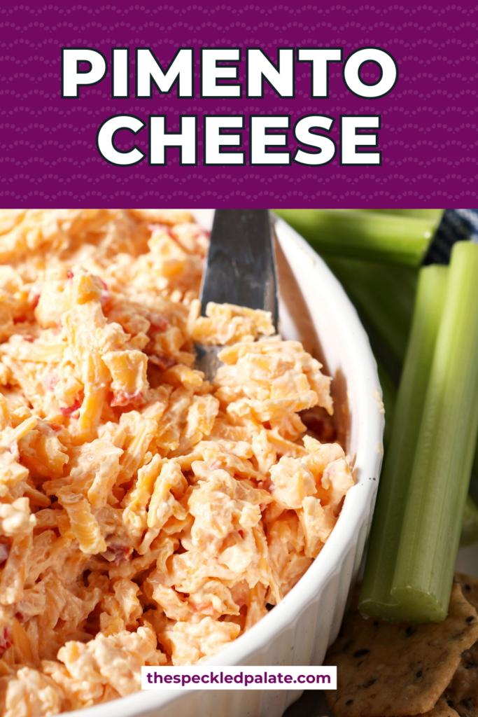 A knife sitting in a white bowl of pimento cheese surrounded by crackers and celery sticks with the text pimento cheese