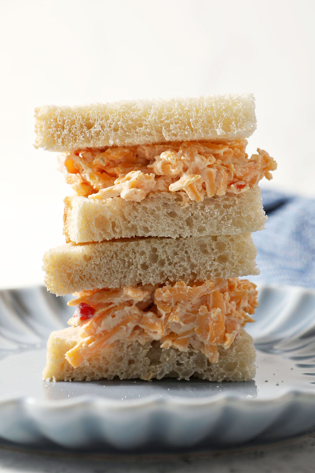 Close up of two triangular pimento cheese sandwiches on a blue plate