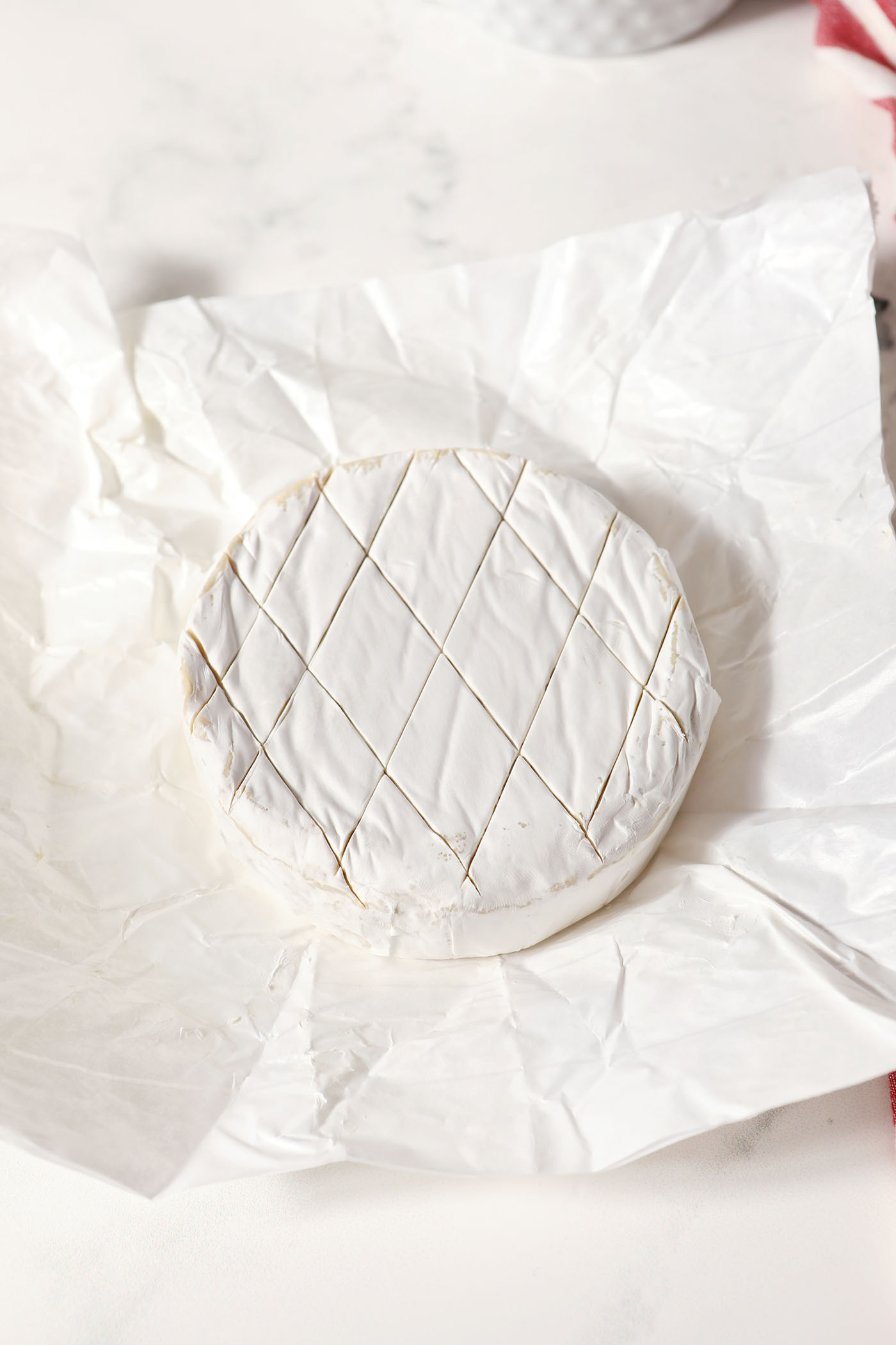 Closeup of a scored wheel of brie on paper