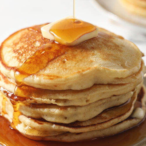 Closeup of syrup pouring on top of a stack of pancakes made from homemade pancake mix