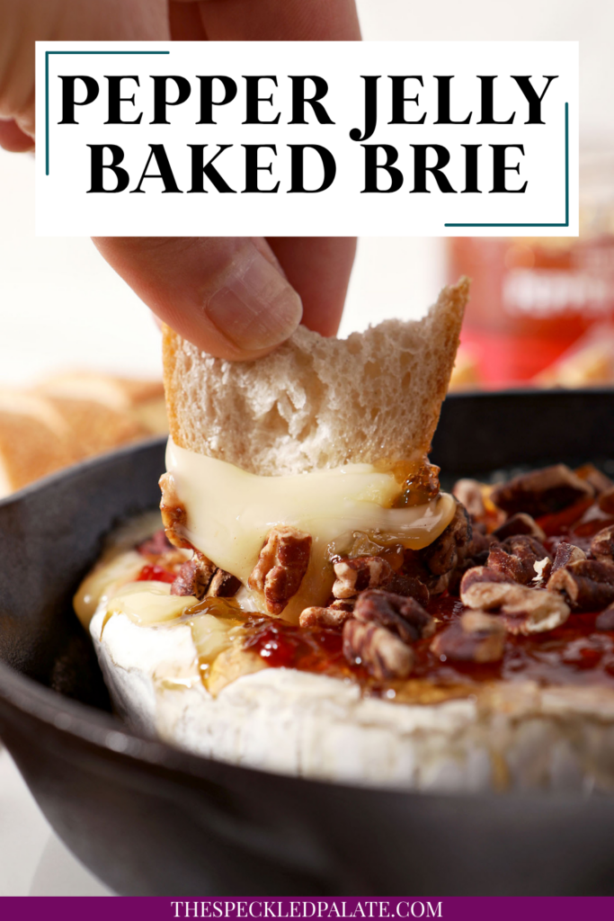 A baguette round is lifted out of a skillet holding Baked Brie with Pepper Jelly and Toasted Pecans with the text pepper jelly baked brie