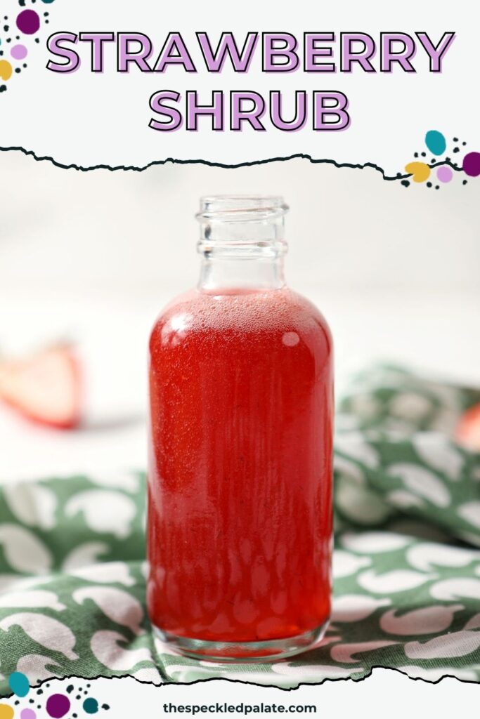 A bottle of homemade strawberry shrub syrup on a green patterned linen with the text strawberry shrub